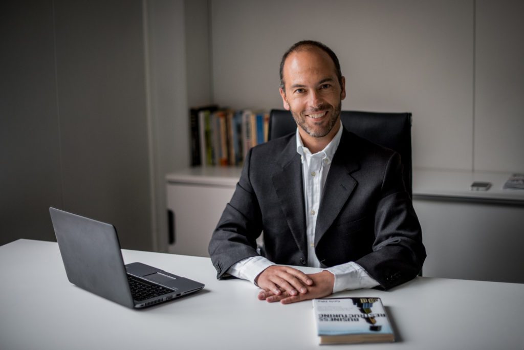 Retrato corporativo de um executivo sentado à secretária com portátil