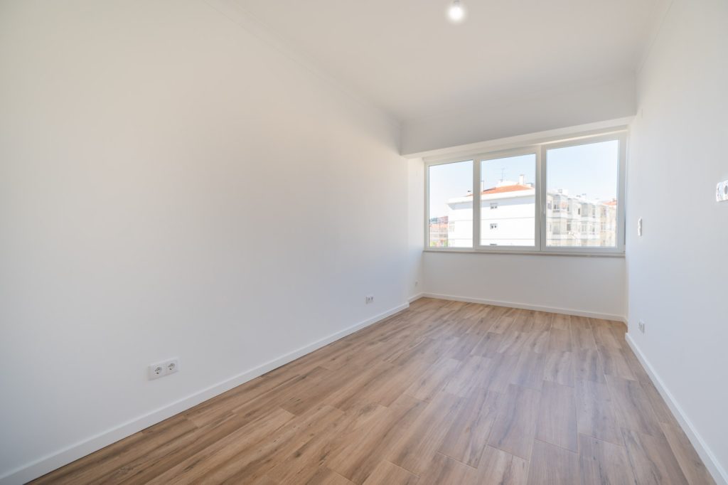 Antes do staging virtual: quarto vazio com chão de madeira e janela