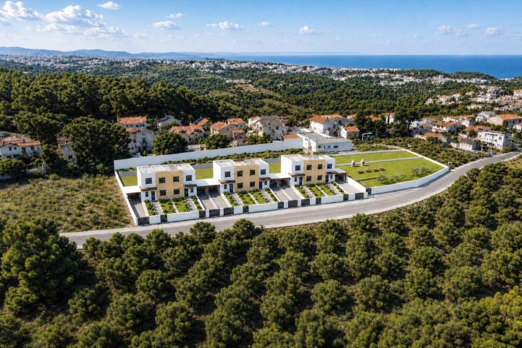 Visualização com IA: vista aérea das seis moradias Casas do Pinhal, com o mar da Ericeira ao fundo