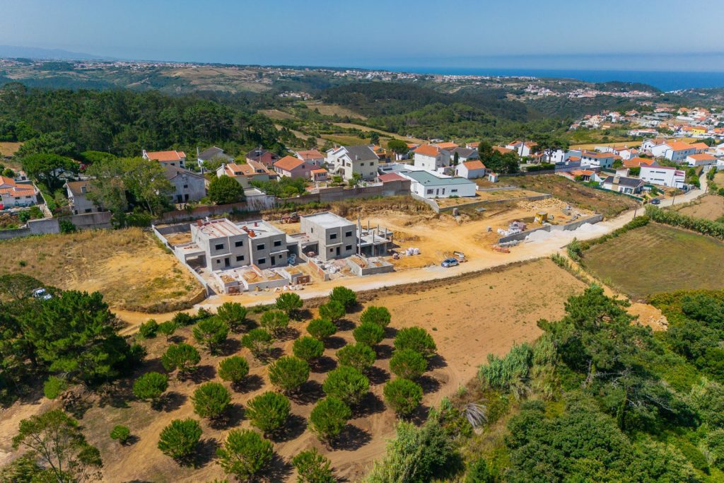 Casas do Pinhal em obra: vista aérea de drone do terreno no Zambujal, Ericeira, com o mar ao fundo