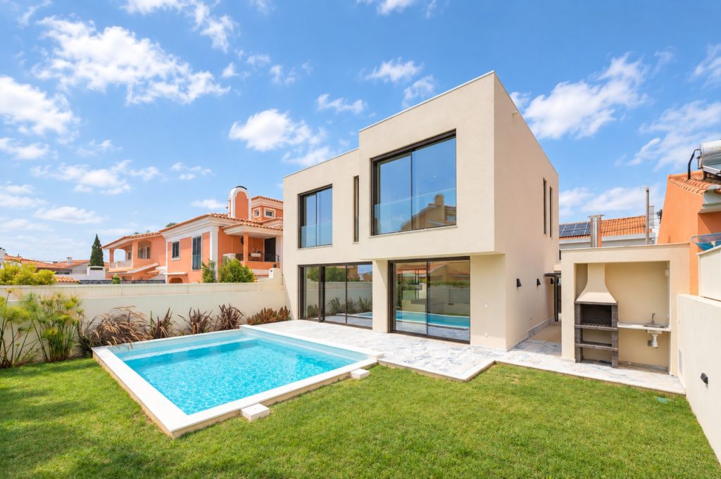 Exterior de moradia moderna com piscina, relvado e churrasqueira