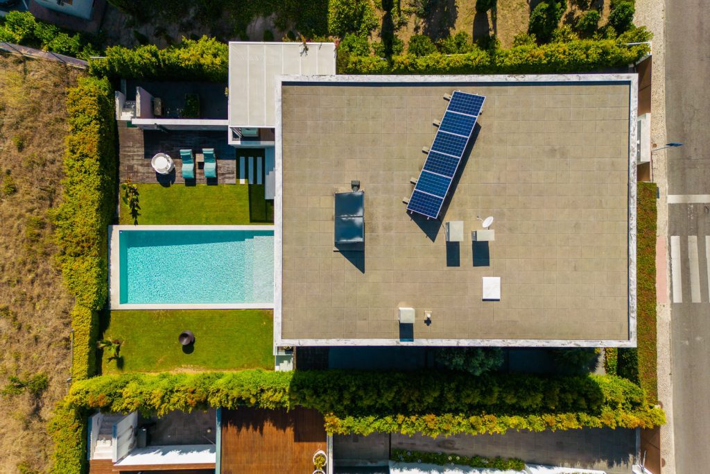 Vista aérea de drone de moradia com piscina, jardim e painéis solares na cobertura